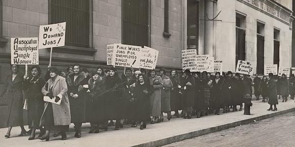 Black and white image of women holding signs during job demand parade, 1933